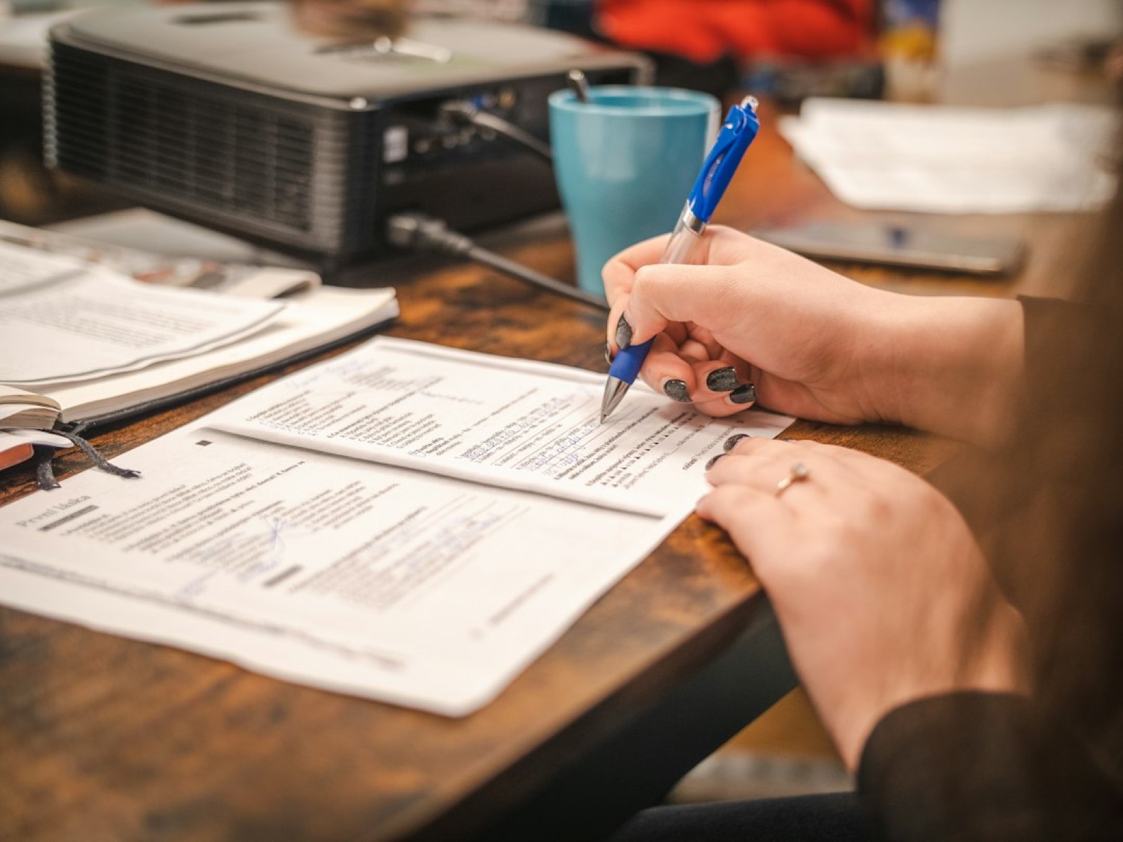 Personne consultant des documents administratifs sur un bureau, stylo à la main